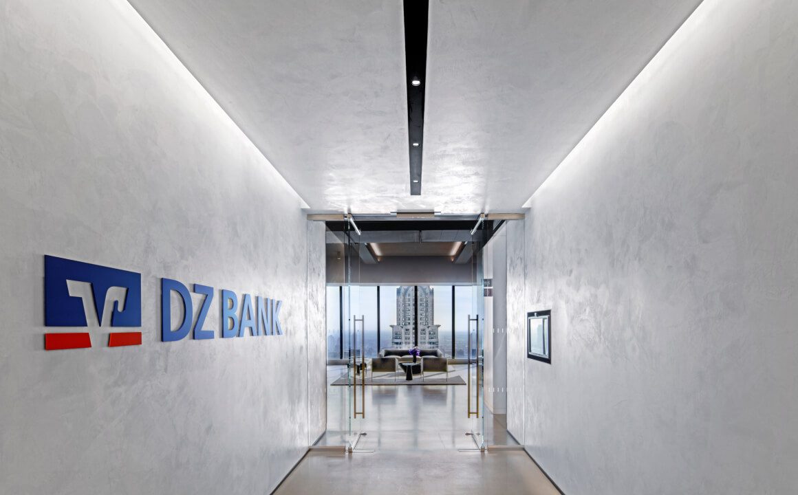 The office of the DZ BANK New York branch: a corridor boasting DZ BANK’s logo and word mark in brand colors on the wall. It leads to a conference room, through the window the Manhattan skyline can be seen.